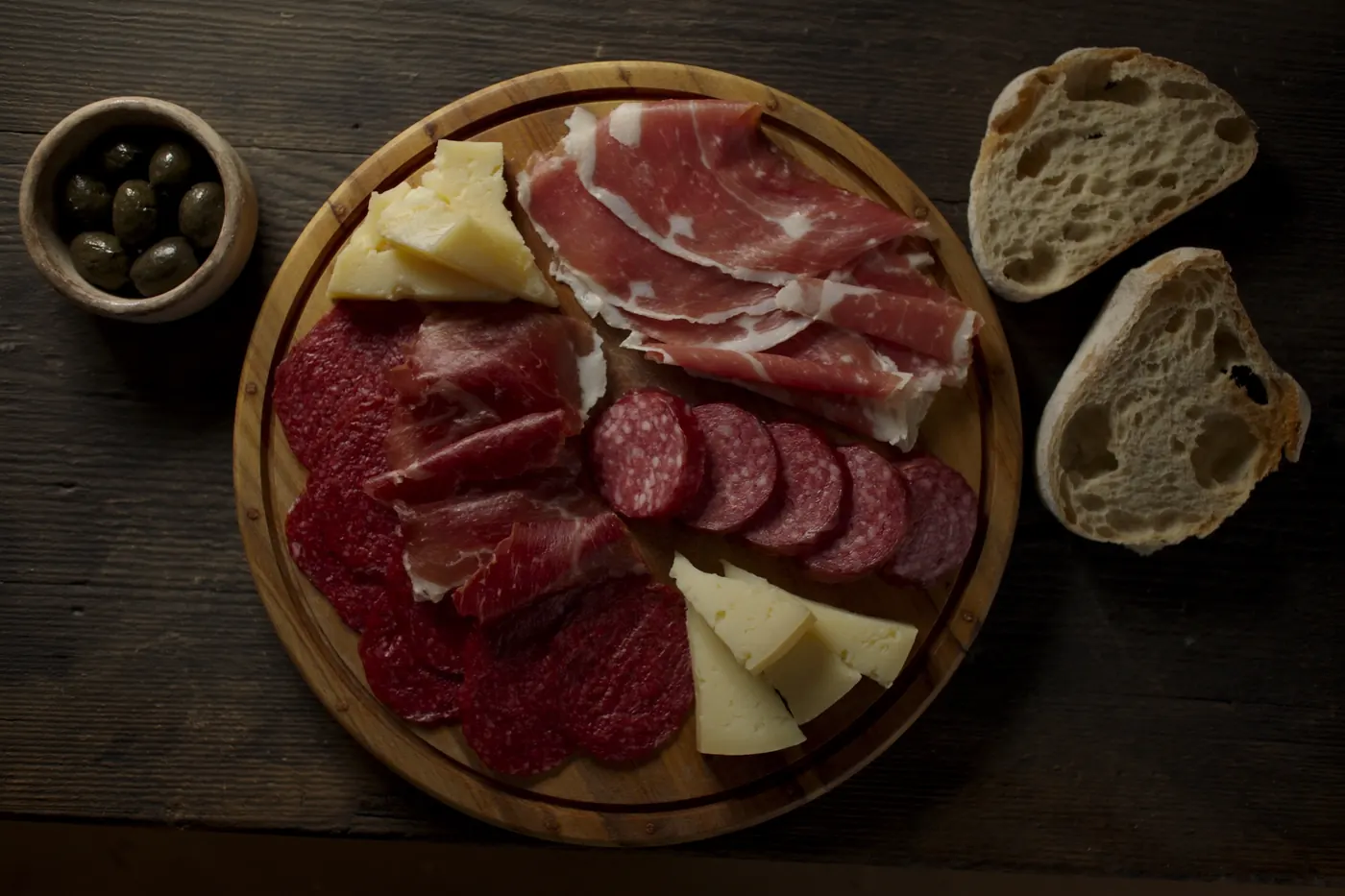 A rustic board of cured meats, aged cheese, olives and homemade bread